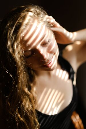Close up portrait of young girl with striped shadows. Concept of private photo session and beautiful...
