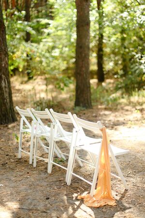 White chairs in garden for bridal ceremony. Concept of outdoor wedding.の写真素材