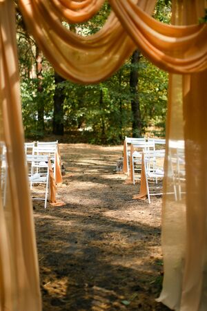 White wooden chairs near altar in park. Concept of celebrating wedding ceremoy outside in forest.の写真素材