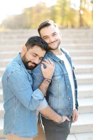 Caucasian young gays hugging in concrete stairs background and wearing jeans shirts. Concept of same sex couple and relationship.の写真素材
