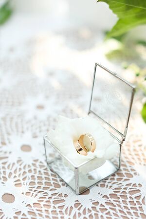 Wedding rings on white rose in little transparent box. Concept of bridal prepations and components.