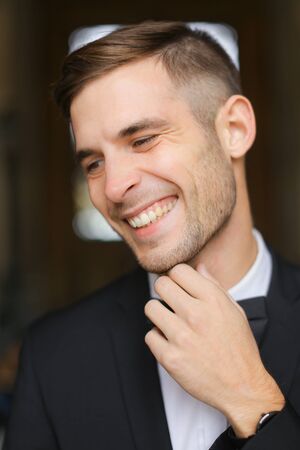 Portrait of young smiling man wearing black suit with bow tie and white shirt. Concept of male model.の写真素材