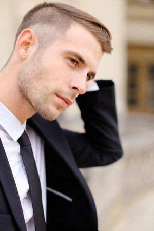 Closeup portrait of young handsome caucasian man wearing balck suit and tie. Concept of male fashionable model and groom photo session.の写真素材