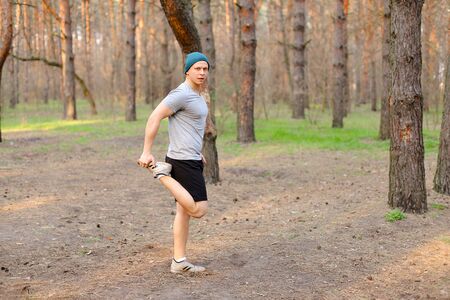 Young boy doing stretch marks in park morning. Concept of workout on nature and fitness exercises....