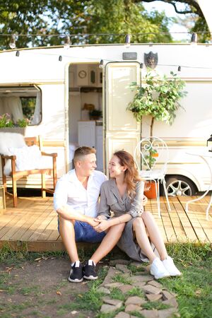 Young european woman and husband standing near house on wheels and hugging. Concept of summer vacations and happy married couple.の写真素材