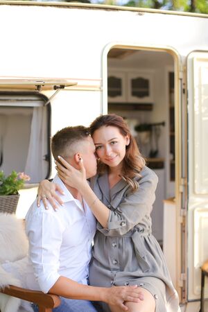 Portrait of young nice woman hugging man near house on wheels. Concept of happy couple and summer vacations.の写真素材