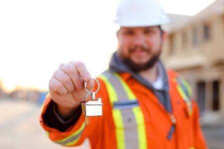Focus on keys from new house in foreman hands on construction site. Concept of world leading estate...