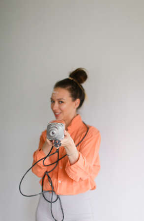 Focus on drill, young woman holding tool and wearing orange shirt, isolated background. Concept of home repairs and skillful attractive wife.の写真素材