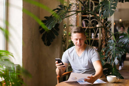 European young confident businessman working with documents at cafe. Concept of work on break and freelance job.の写真素材