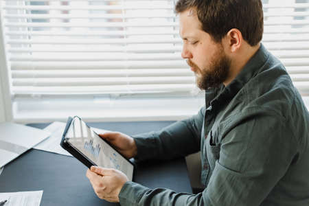 Closeup male businessman using tablet and looking at graphs on screen. Concept of business project...
