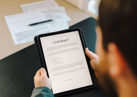 Businessman showing contract template on tablet at office. Concept of documents filling and sample.