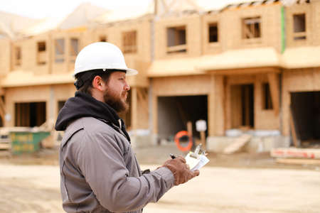 European buider drawing plan in notebook at construction site and wearing hardhat. Concept of architectural profession and house building.の写真素材