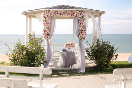 Amazing wedding arch decorated by roses with lake in background. Concept of outdoor bridal ceremony place.の写真素材