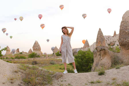 Blonde girl standing with many hot air balloons on background in Capadocia. Concept of festival in Turkey.の写真素材