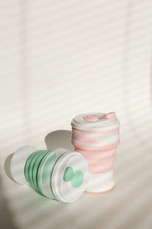 Silicone reusable straw bottles for water or drinks in light background with copy space. Concept of...