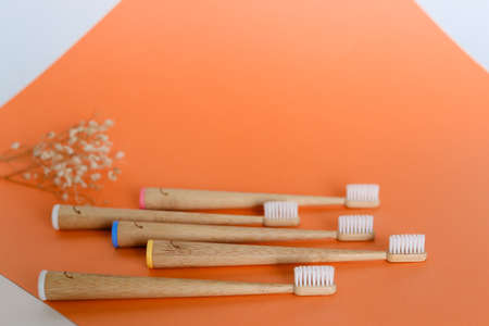 Set of five wooden bamboo toothbrushes on orange background with copy space. Concept of reducang plastic, ecofriendly products in online shop.の写真素材