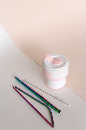 Silicone reusable straw cup with stainless steel straws in ligtht background. Concept of reusing, reducing plastic and ecofriendly products, online shop.の写真素材