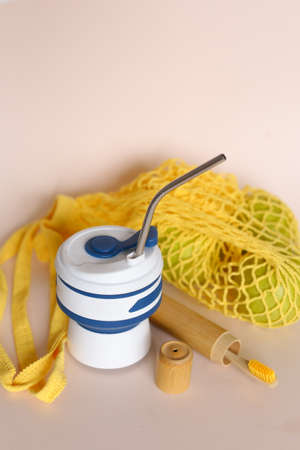 Reusable blue silicone straw cup with metal straws, yellow mesh bag and wooden toothbrush. Concept of ecofriendly products shop and reducing plactic.の写真素材