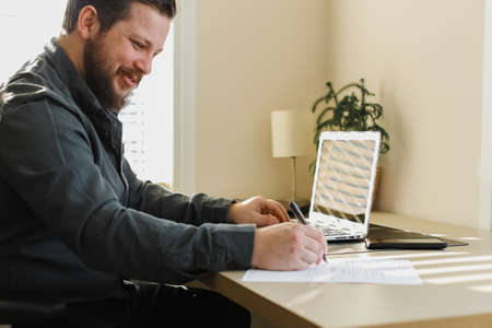 Caucasian businessman writing letter of resignation and using laptop. Concept of writing application...