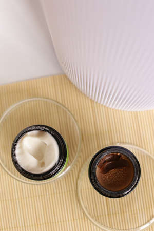 Opened two jars of facial cosmetic white cream and brown mask on wooden table. Concept of cluelty free, organic, kosher cosmetics is great for dry and rough skin.の写真素材