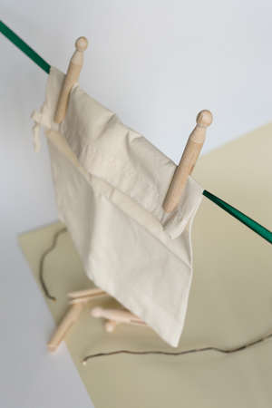 White tissue pouch hanging on wooden eco clothespins in light background. Concept of reducing plastic and ecological organic products online shop.の写真素材