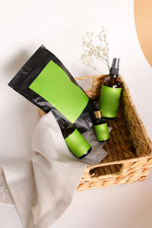 Black doy pack and spray bottles  cosmetic products in wicker basket, green space for your brand.の写真素材