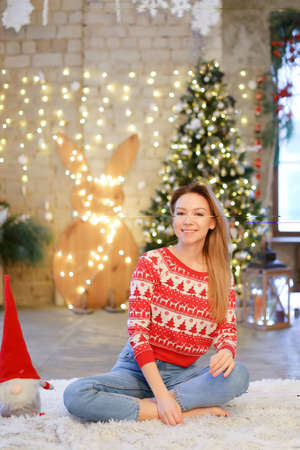 Caucasian girl sitting on blanket with Christmas tree in background.の写真素材