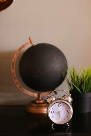 Black decorative stylish globe and clock standing on table near houseplant.の写真素材