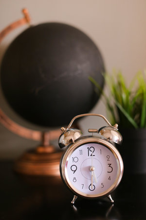 Black stylish globe and clock standing on table near houseplant.の写真素材