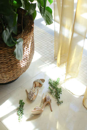 Bride shoes lying near basket with housepant.の写真素材