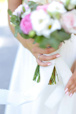 Focus on ring, bride keeping bouquet of roses.の写真素材