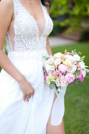 Bride keeping bouquet of flowers and walking in grass background.の写真素材