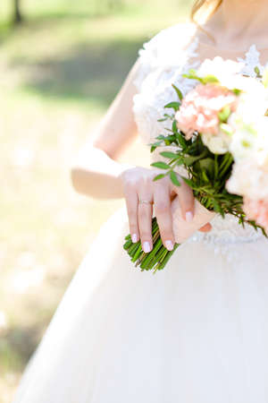 Focus on golden ring, bride keeping bouquet of roses.の写真素材