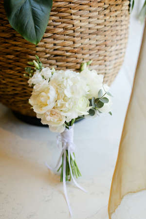 Wedding bouquet of white roses near basket with houseplants.の写真素材