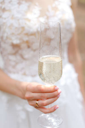 Close up wineglass with champagne in bride hands.の写真素材