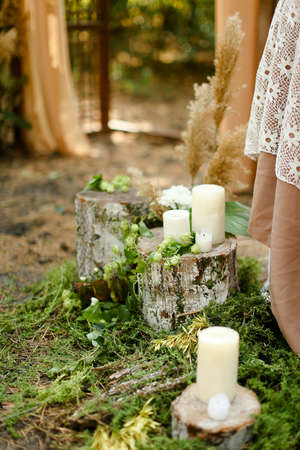 White candles on wooden stumps near wedding altar.の写真素材