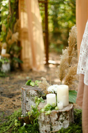 White paraffin candles on wood stumps near wedding altar.の写真素材