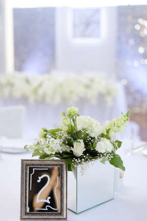 Bouquet of roses near frame with number two on banquet table.の写真素材