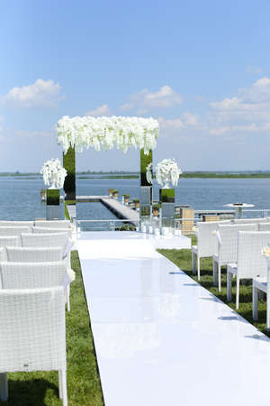 White amazing wedding arch and chairs near lake.の写真素材