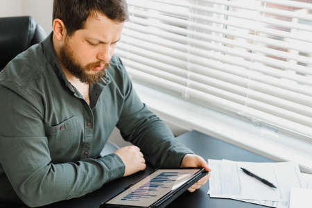 Serious male director using digital tablet and working with documents.の写真素材