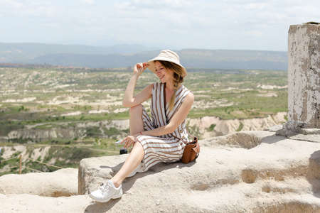 Girl sitting on rock, beautiful landscape in background, Cappadocia.の写真素材