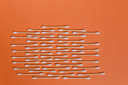Many cotton tipped buds in row on orange background.