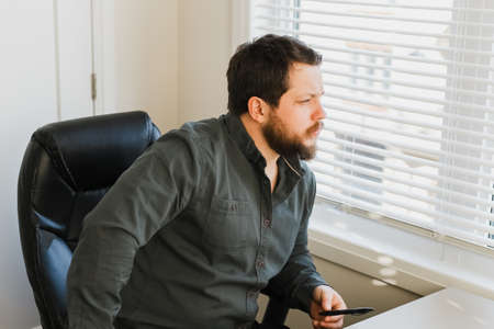 Male business director sitting at office archair, holding pen and looking at window.の写真素材