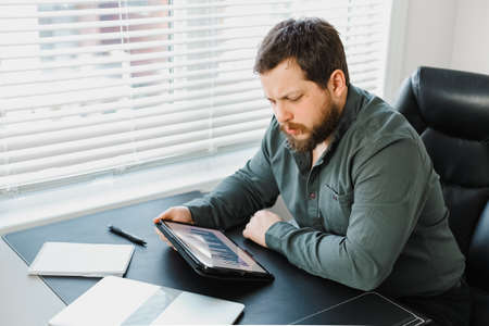 Serious male executive using digital tablet and working with documents.の写真素材