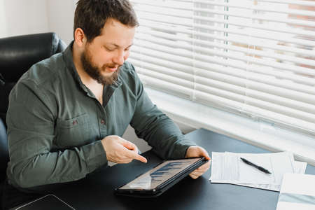Serious male financier using digital tablet and working with documents.の写真素材