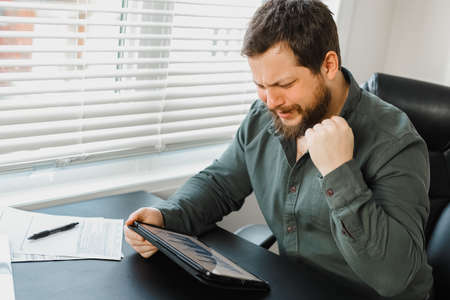Successful male financier using digital tablet and working with documents.の写真素材