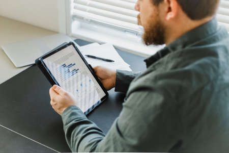 Closeup financier using tablet and looking at graphs on screen.の写真素材
