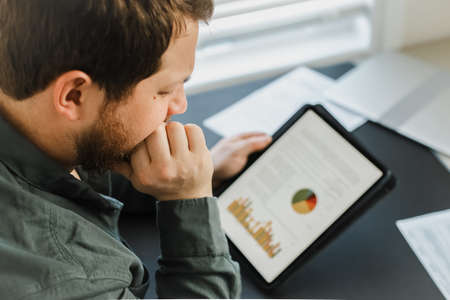 Closeup financier using tablet and looking at graphs with diagrams on screen.の写真素材