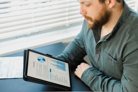 Economist working with graphs and diagrams on tablet at office.の写真素材