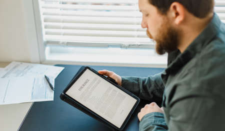 Businessman reading insurance on tablet screen at office.の写真素材